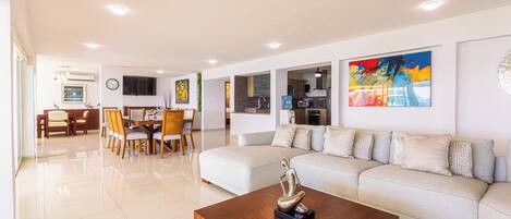 A modern living room with a sofa, coffee table, and dining area.