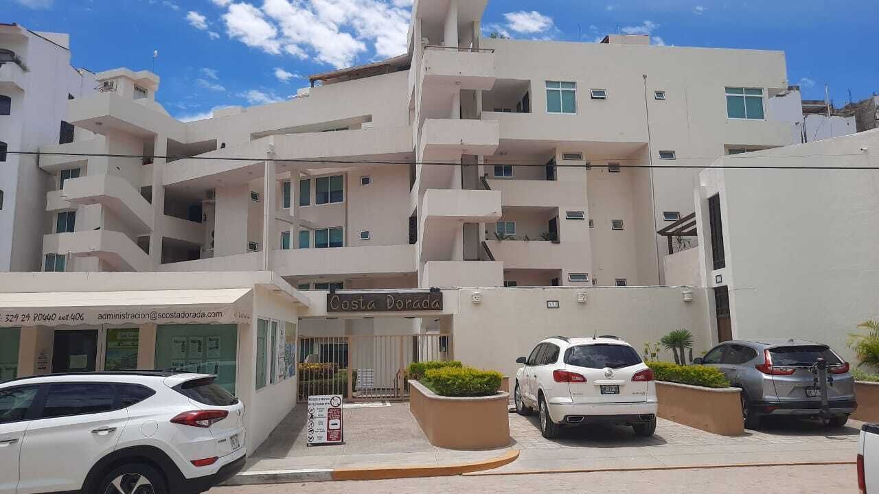 A multi-story building with a sign reading "Costa Dorada." There are several parked cars in front, and a small signboard with text and symbols.