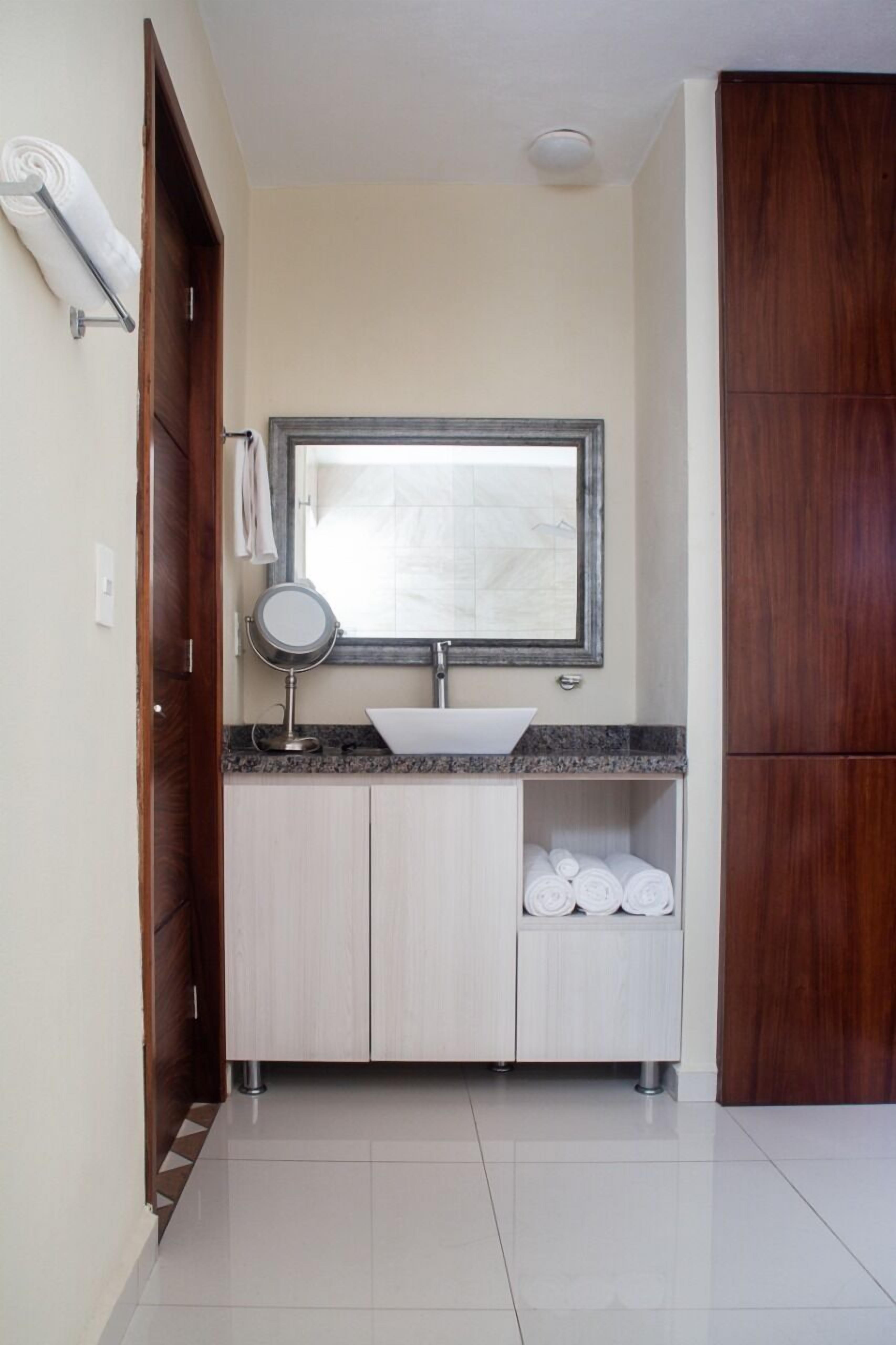A bathroom with a sink, mirror, and towel storage.