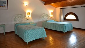 Habitación con dos camas, piso de madera y techo inclinado.