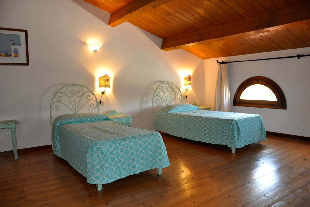Une chambre avec deux lits, un plancher en bois et un plafond en pente.