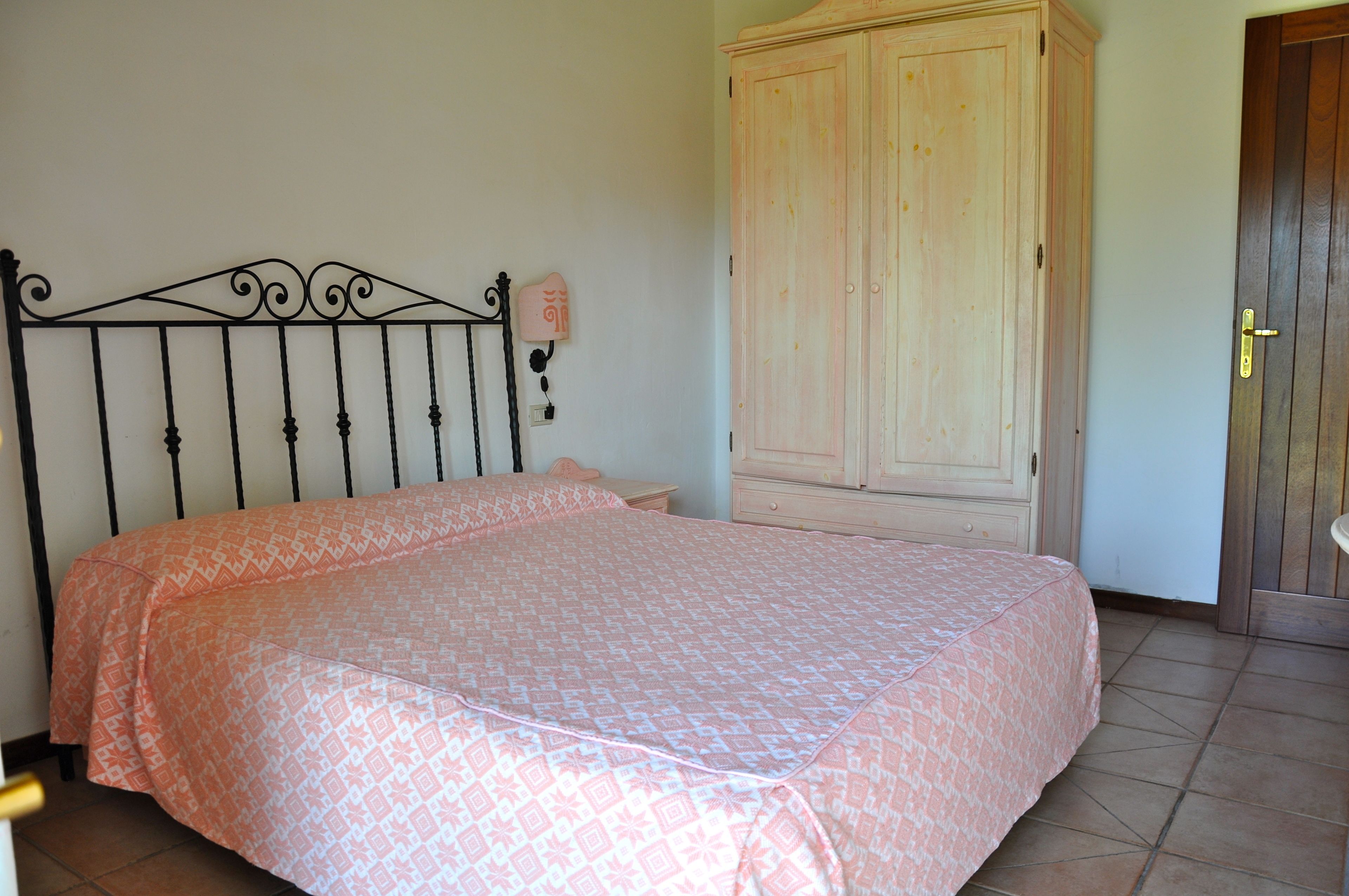 A bedroom with a bed, a wardrobe, and a door.