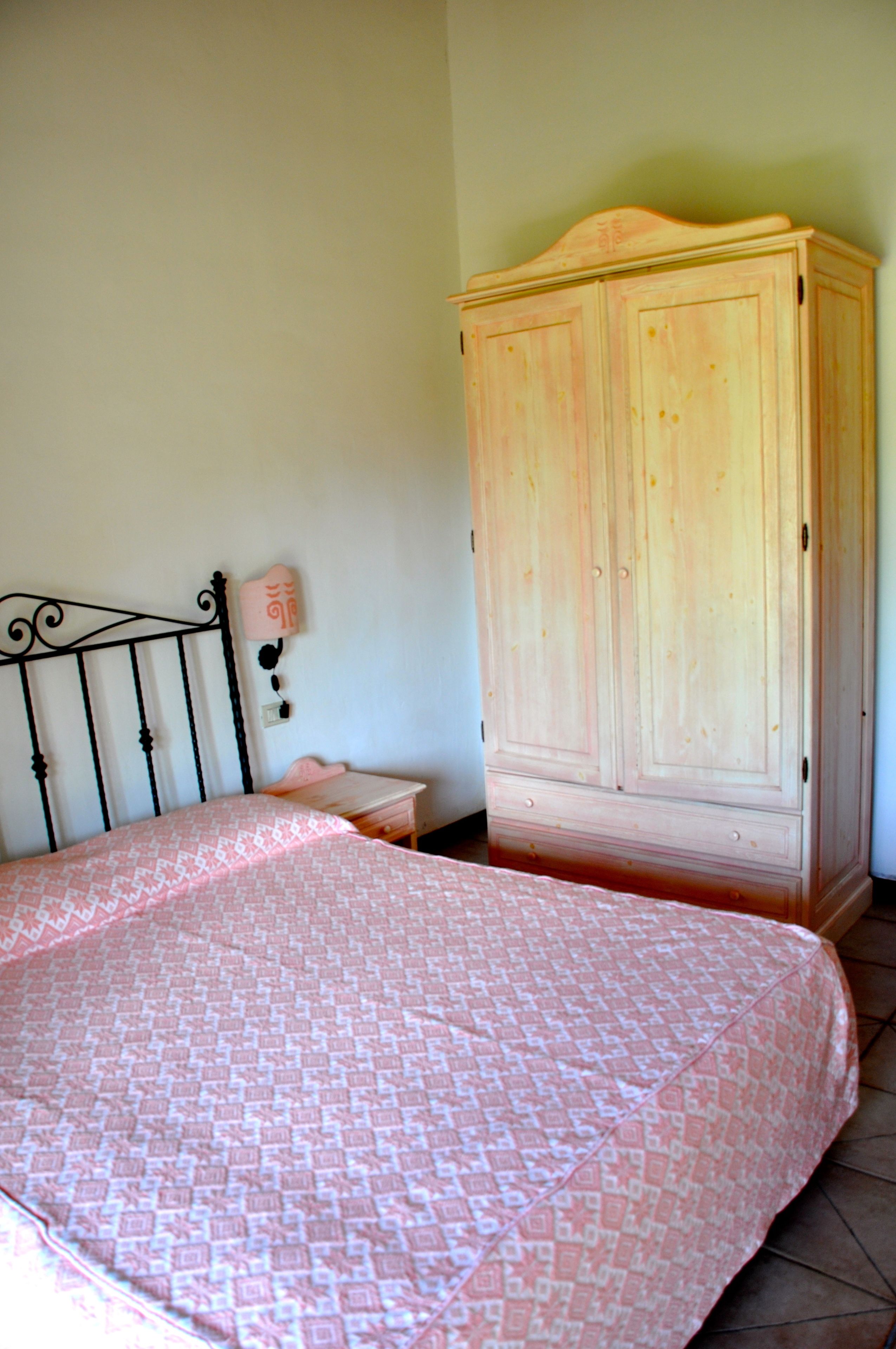 A bedroom with a bed, a wardrobe, and a nightstand.
