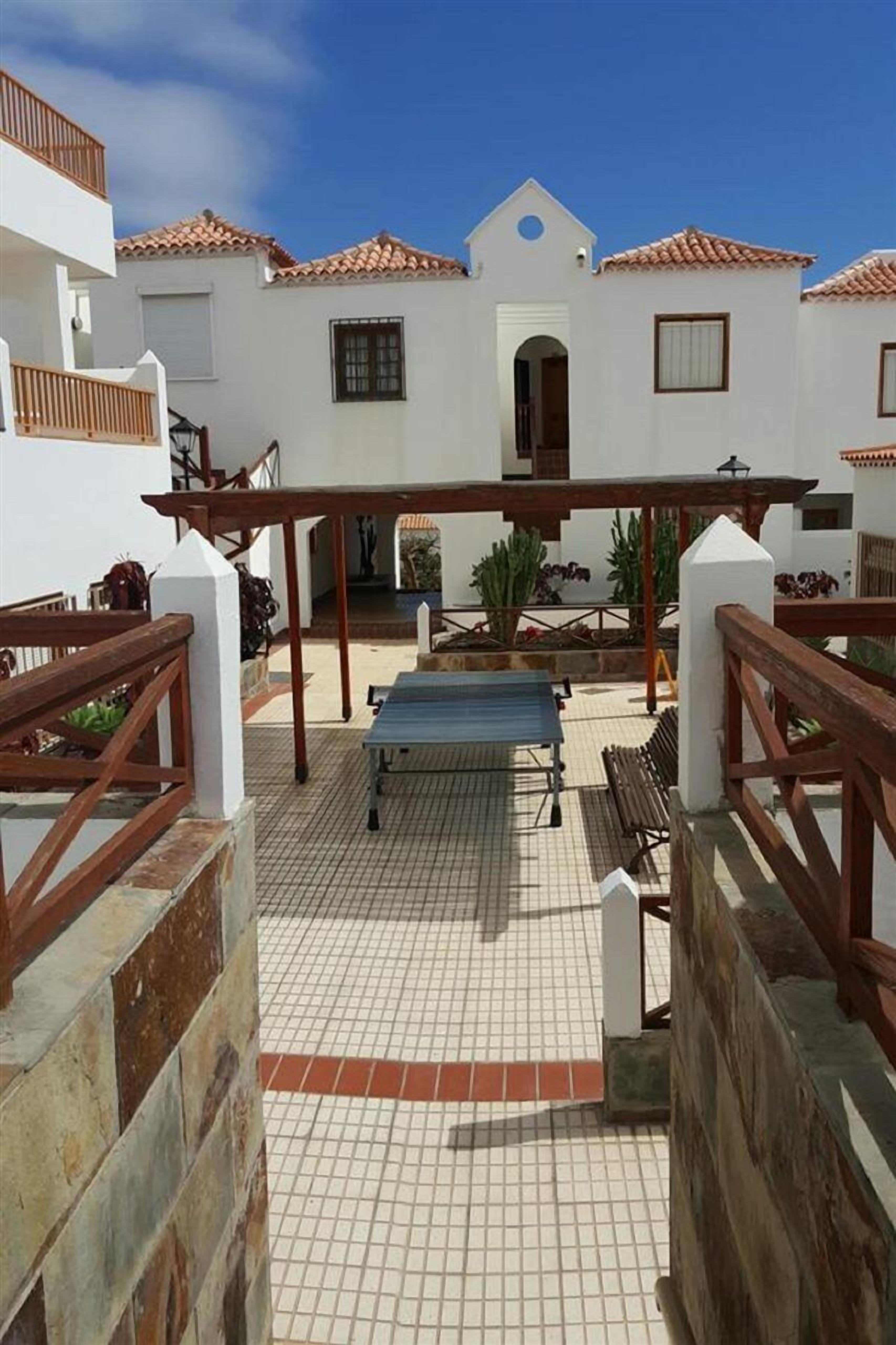 A courtyard with a covered seating area, a small table, and a bench.