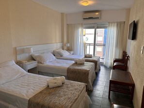Quarto de hotel com duas camas, uma escrivaninha, cadeiras, telefone e ar condicionado.