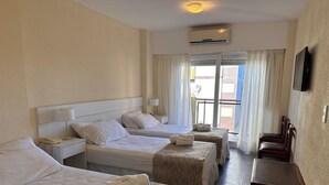 Hotellihuone, jossa on kaksi sänkyä, työpöytä ja näkymä ulos.