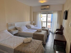 Quarto de hotel com duas camas, uma escrivaninha e vista para o exterior.