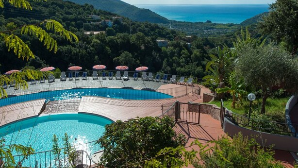 Zona de piscina con vistas al mar y colinas.
