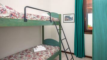 Un letto a castello con biancheria da letto floreale, una scala, un quadro appeso al muro e una finestra con tende.