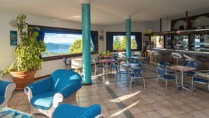 Una terraza con sillas azules, una zona de bar y una planta grande en maceta.
