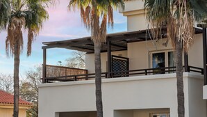Un bâtiment à deux étages, doté de balcons et d’un rez-de-chaussée en pierre, avec un ciel dégagé.