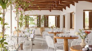 A restaurant with outdoor seating, wooden beams, and potted plants.