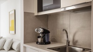 Une cuisine moderne équipée d’une machine à expresso intégrée, d’un évier et d’un four à micro-ondes placé au-dessus du plan de travail.