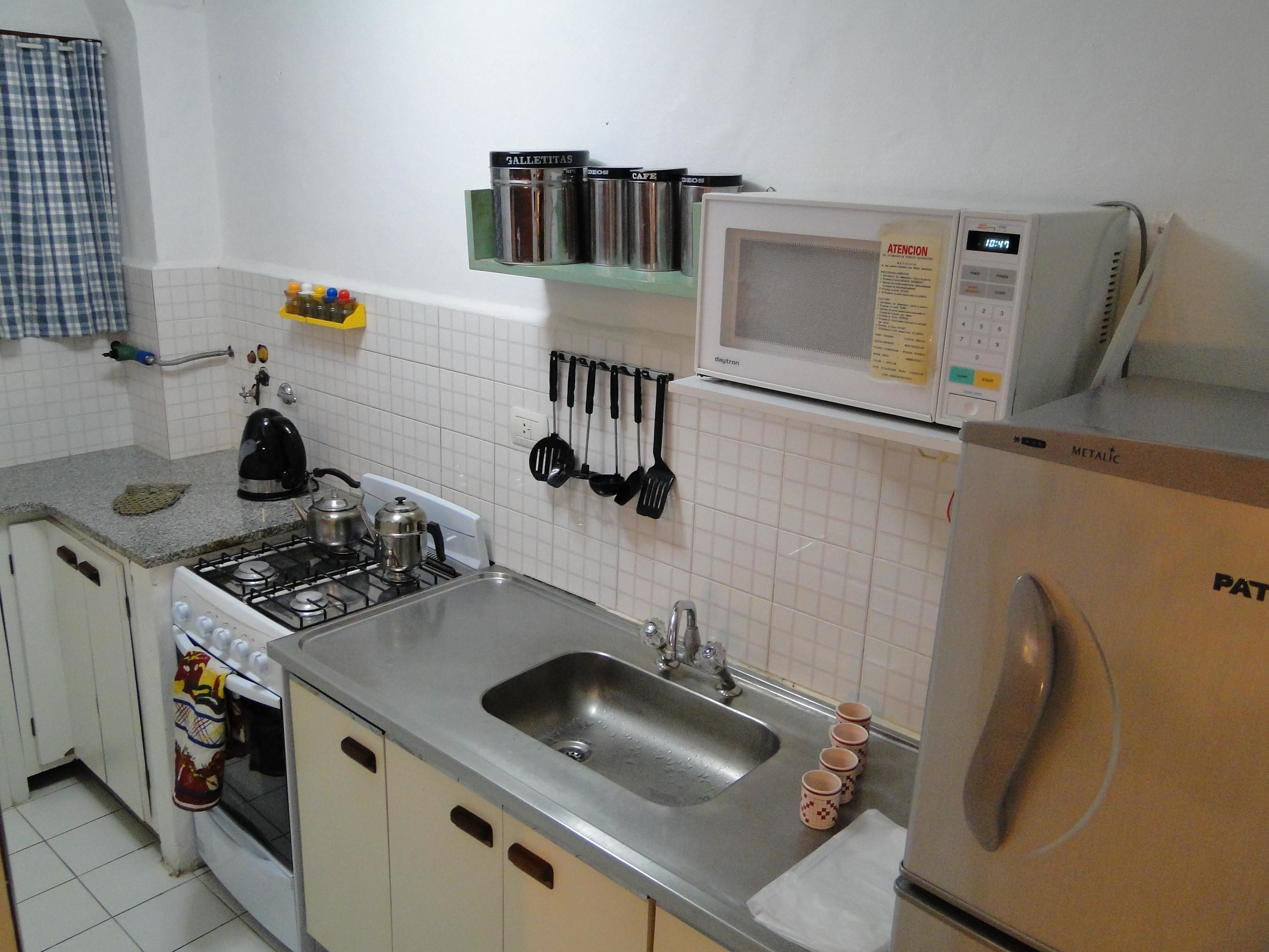 A kitchen with a stove, sink, microwave, and cabinets.