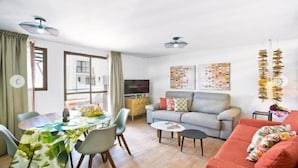 Un salon comprenant un canapé, une table basse, une table à manger avec des chaises et un téléviseur.