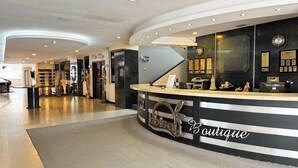 A hotel reception area with a curved reception desk, a clock, and framed awards on the wall. - Hotel Tibisay  (Milla)