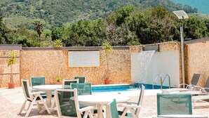 A pool area with a stone wall, a waterfall feature, and a sign. - Hotel Tibisay  (Milla)