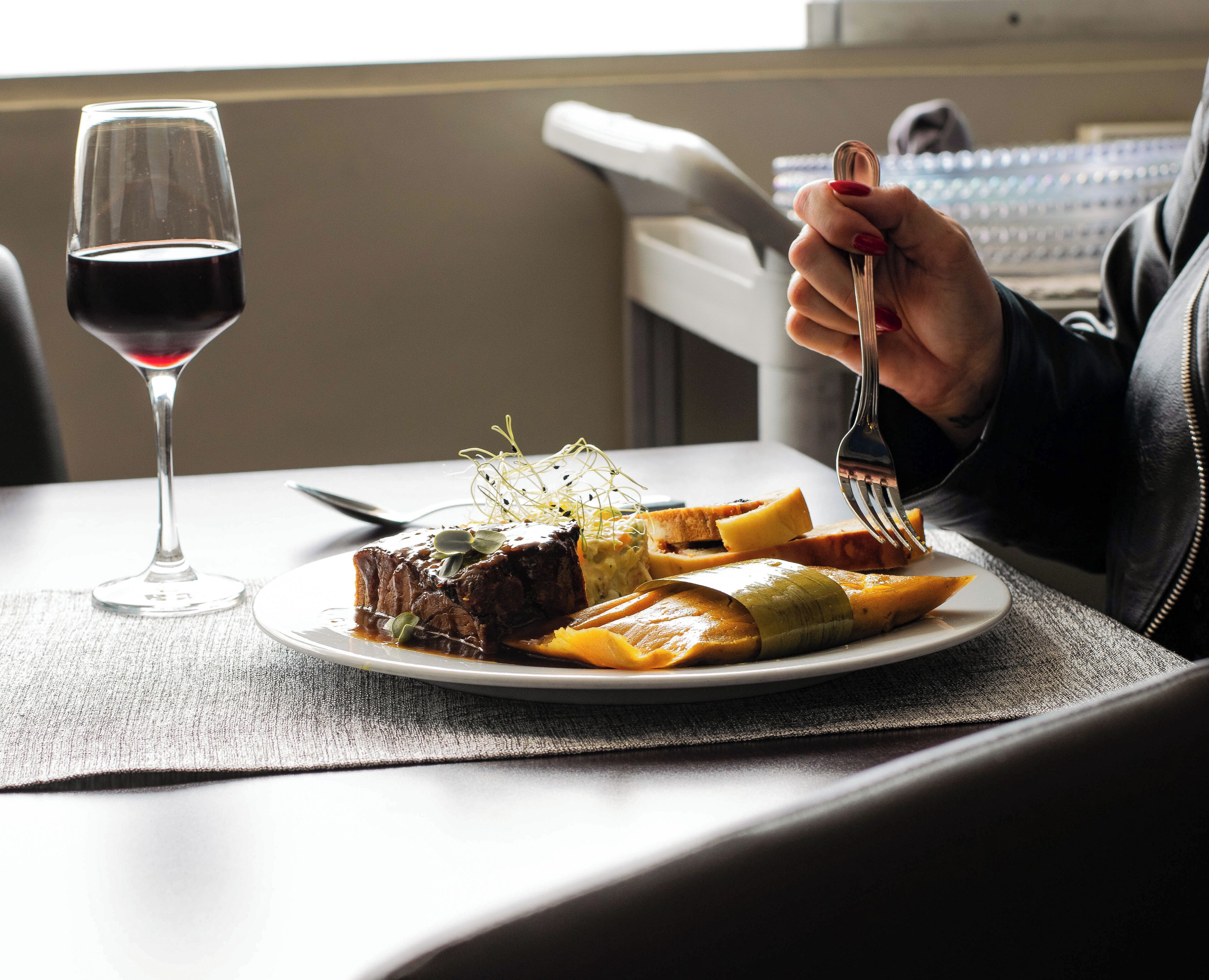 A plate of food with a glass of red wine on a table.