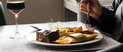 A plate of food with a glass of red wine on a table.