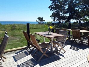 A wooden deck with outdoor seating, overlooking a body of water and greenery. - Smygehus Havsbad (Trelleborg)