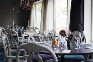 A dining area with a round table set for a meal, surrounded by white chairs with blue cushions. - Smygehus Havsbad (Trelleborg)