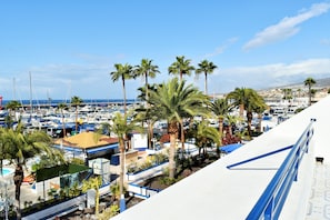 A marina with boats, palm trees, and buildings. - Apartamentos Puerto Colon Club (Adeje)