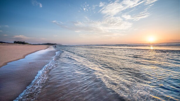 Una playa con olas suaves y cielo despejado.