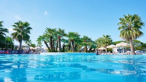 Una piscina con palme e lettini da sole.