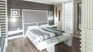 Una camera da letto con un letto, una ventola a soffitto, un comodino e una finestra con persiane.