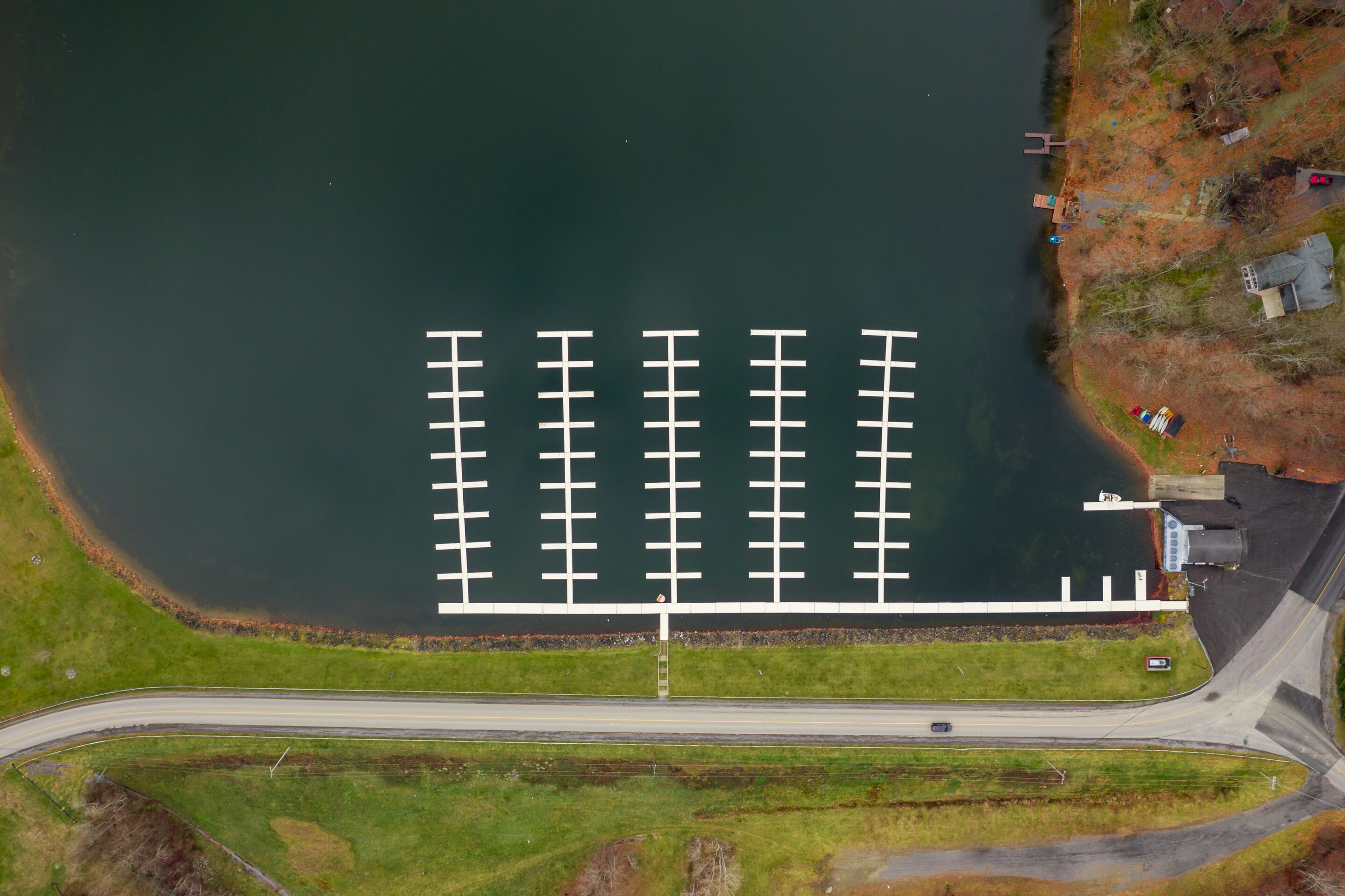 An aerial view of a marina with docks, a road, and a grassy area.