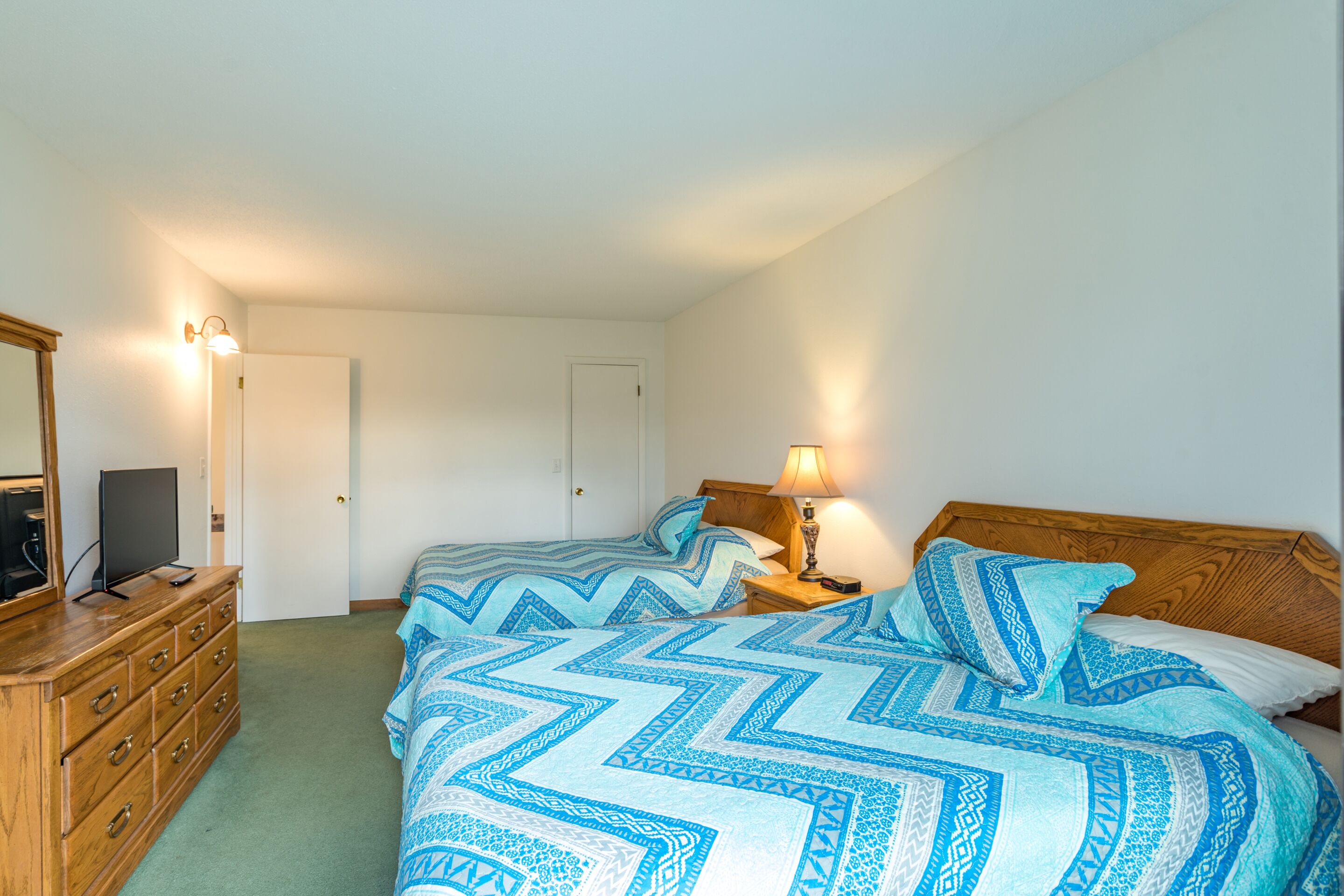 Un dormitorio con dos camas, un aparador, un televisor y una lámpara.