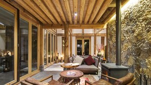 A cozy interior with wooden beams, a stone wall, and a fireplace.