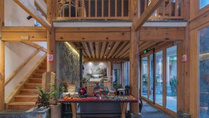 A wooden interior with a staircase, a table with various items, and large windows.