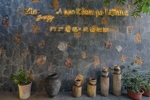 A stone wall with Chinese characters and a potted plant. - Arro Khampa by Zinc Journey Lijiang (Lijiang)