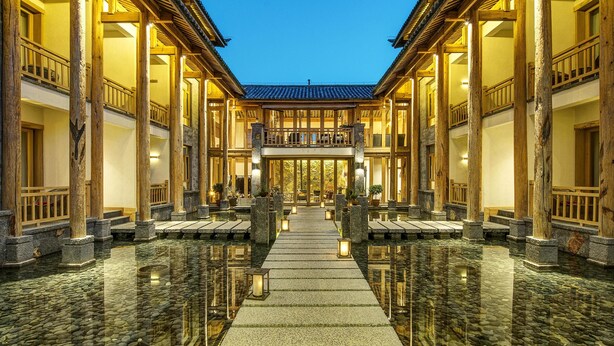 A traditional building with a central courtyard, wooden pillars, and a tiled roof.