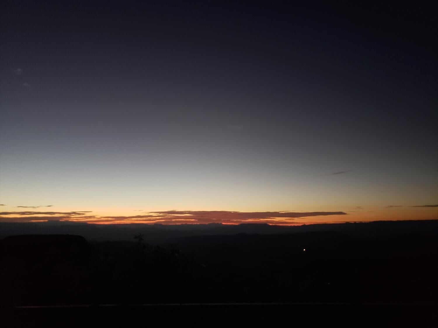 A nighttime landscape with a clear sky and distant horizon.
