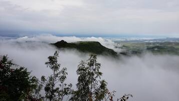Un paisaje montañoso con una estructura en una colina, rodeada de nubes.