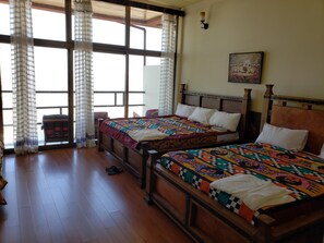 Two beds, a bench, and a window with a view.