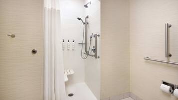 A modern bathroom with a walk-in shower, grab bars, and a toilet paper holder.