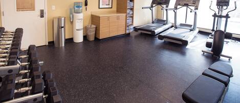 A gym with treadmills, dumbbells, and a water dispenser.