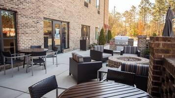 Une terrasse extérieure avec des murs en briques, des sièges et un barbecue.