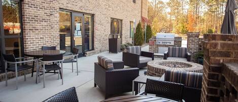 Un patio al aire libre con paredes de ladrillo, mobiliario exterior y una parrilla.
