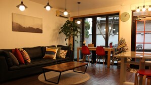A living room with a sofa, a coffee table, and a dining area with a table and chairs. - Bunk Guest House - Hostel (Seoul)