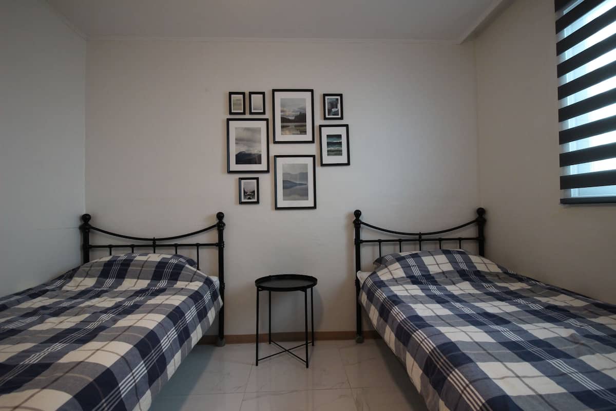 Une chambre avec deux lits, une petite table et un mur orné de tableaux.