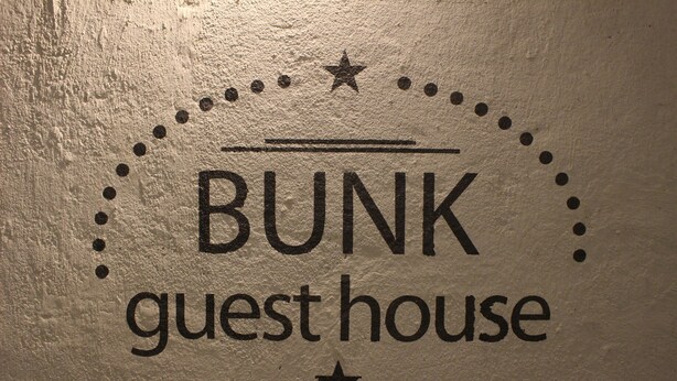 A wall with the text "BUNK guest house" and decorative elements like stars and dots. - Bunk Guest House - Hostel (Seoul)