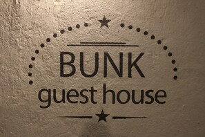 A wall with the text "BUNK guest house" and decorative elements like stars and dots.