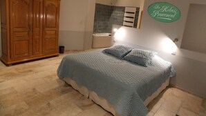 Een slaapkamer met een grote houten garderobe, een bed met een gewatteerde spreideken en een wandlamp.