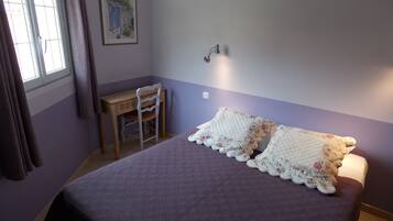 A bedroom with a bed, a desk, and a chair.