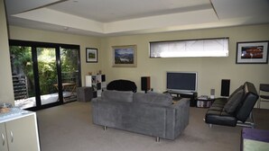 A living room with a grey sofa, a black leather chair, a TV, and a bookshelf. - StudioAt10 (Sandy Bay)