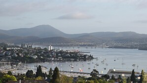 A marina with numerous boats, a bridge in the background, and a hilly landscape. - StudioAt10 (Sandy Bay)